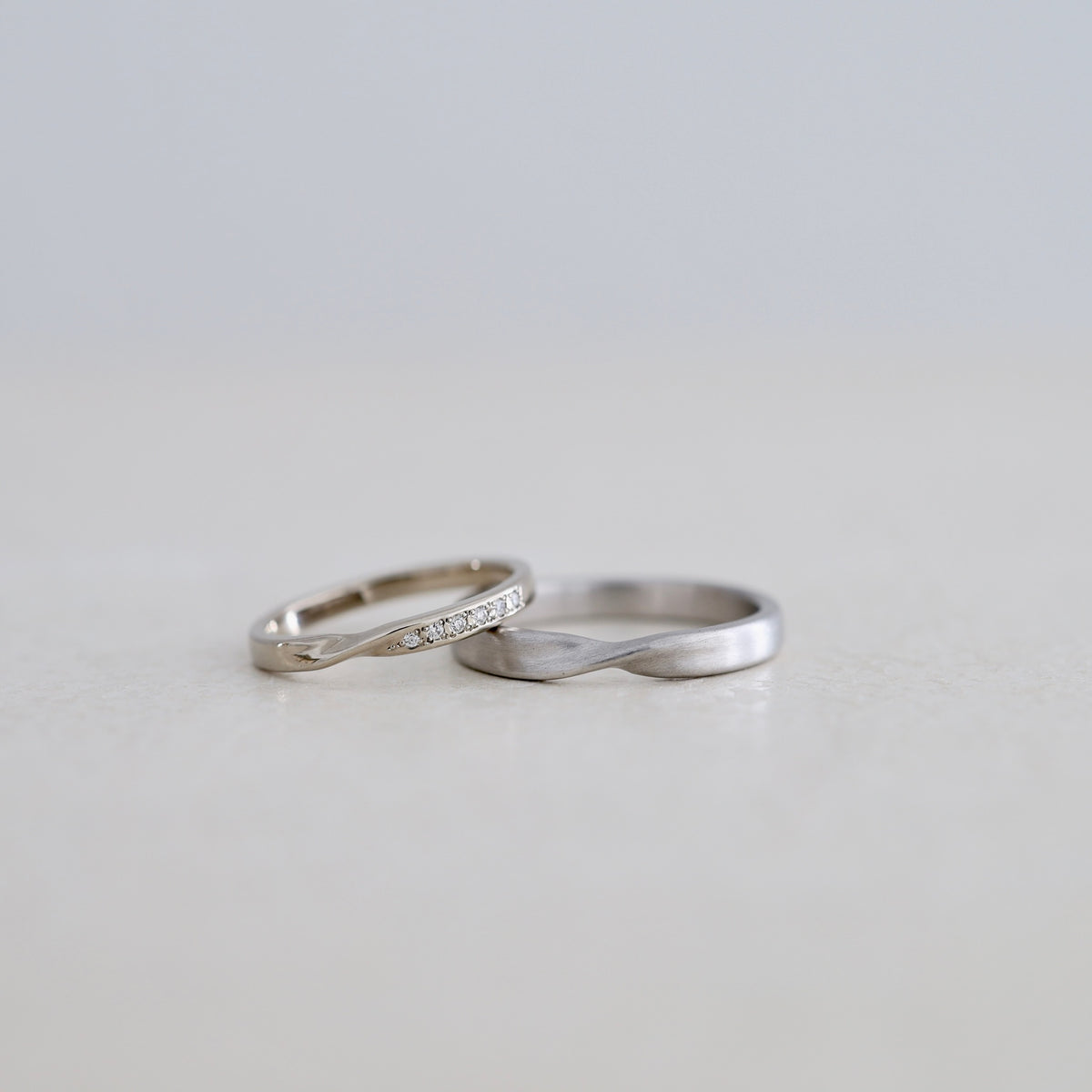 中央をひねるようなデザインのK18ホワイトゴールドとプラチナのマリッジリング（結婚指輪）鏡面仕上げとヘアライン仕上げ エタニティダイヤアレンジ